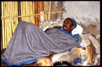 A sick man lying in a bed at home.