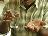 A man takes some drugs with a glass of water.
