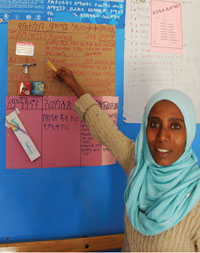 A health worker pointing at a planning chart displayed on the health post wall.