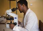 A laboratory technician examines cells and tissues under a microscope.