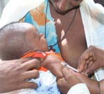 A mother holds their child whilst they are immunized.