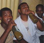 Three men enjoy a bottle of alcoholic drink.
