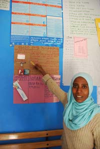A health worker points to a poster on the wall at the health facility.