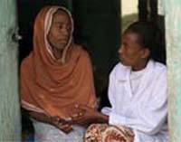 A health worker counsels a woman. They sit side by side and the health worker is holding the woman’s hand.