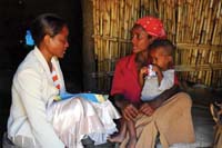A healthcare worker interviewing a woman whilst a child sits on her lap.