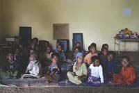 A group of children are sitting together on thg floor.