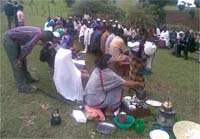 A community gathering. A community member has brought along cooking utensils and equipment.