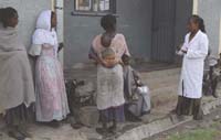A healthcare worker talks to some women outside the health facility.
