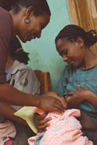 A health worker is showing anew mother how to improve her breastfeeding technique. A baby suckles on her mother’s teat.