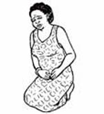 A pregnant woman kneeling down clasping her abdomen in pain.