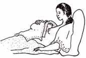 A mother sits up in bed whilst her baby lies on her chest.