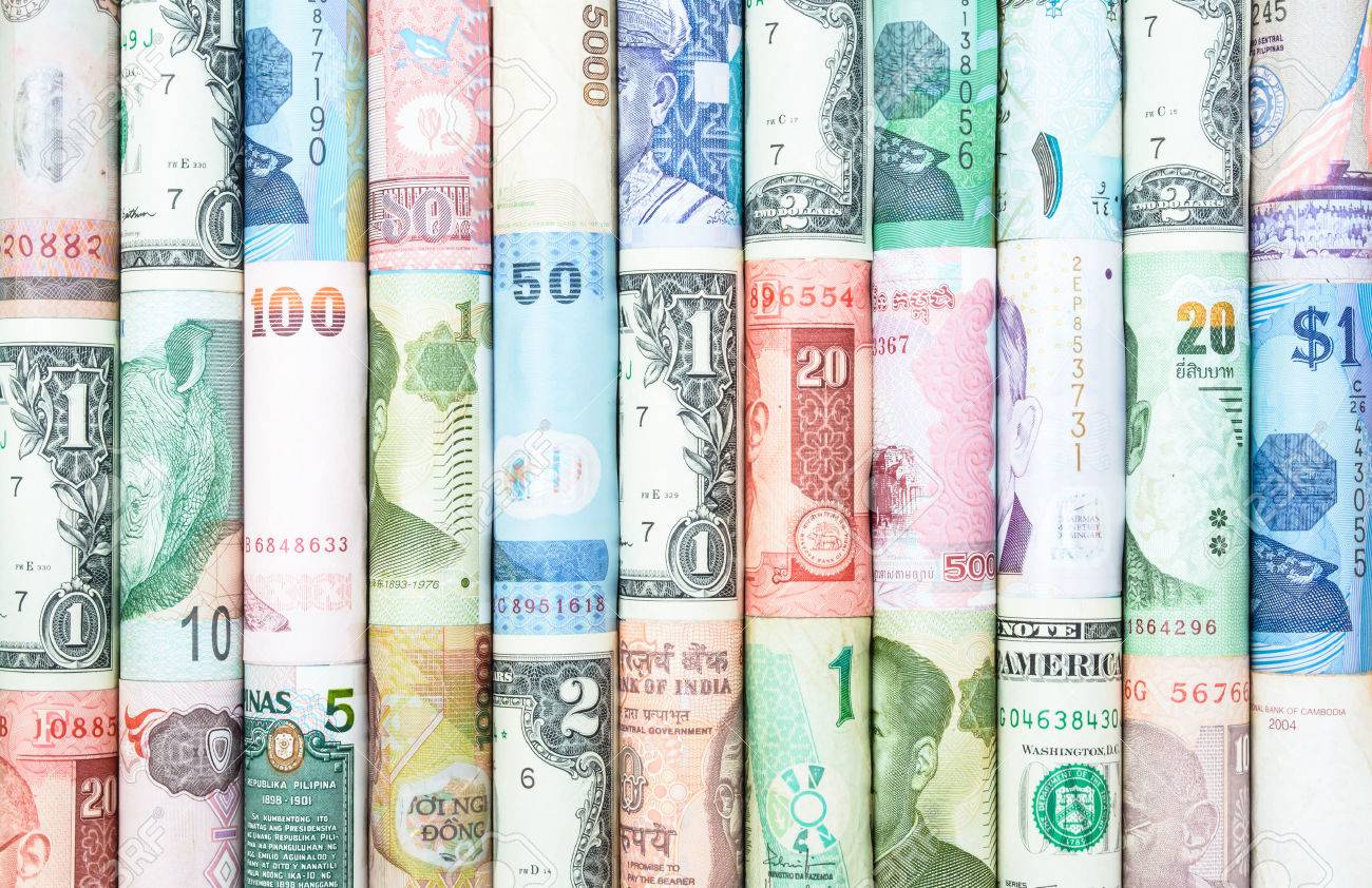 A selection of notes of money from around the world, rolled up and displayed together.