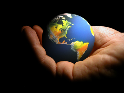 A hand holds a small globe.