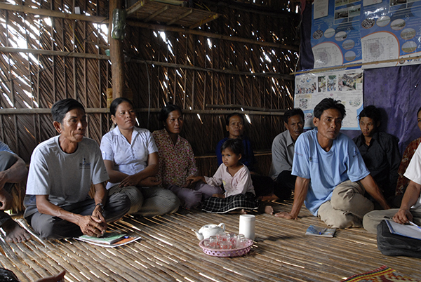 People sat in a circle on a large mat holding a meeting