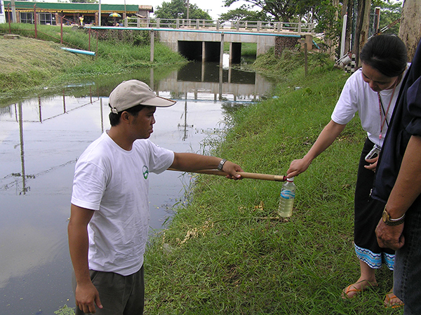 Photo of community members collecting a water sample from a river