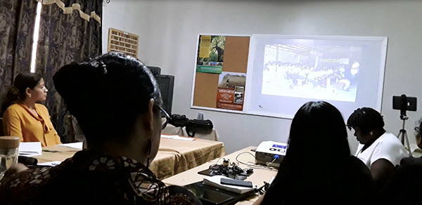 Photo of a video screening event to decision makers with people sat in the foreground and the video screen in the background