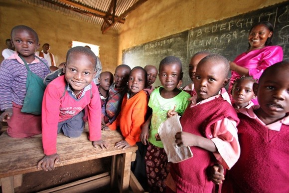 Photograph of children in an African classroom grouped and facing the camera