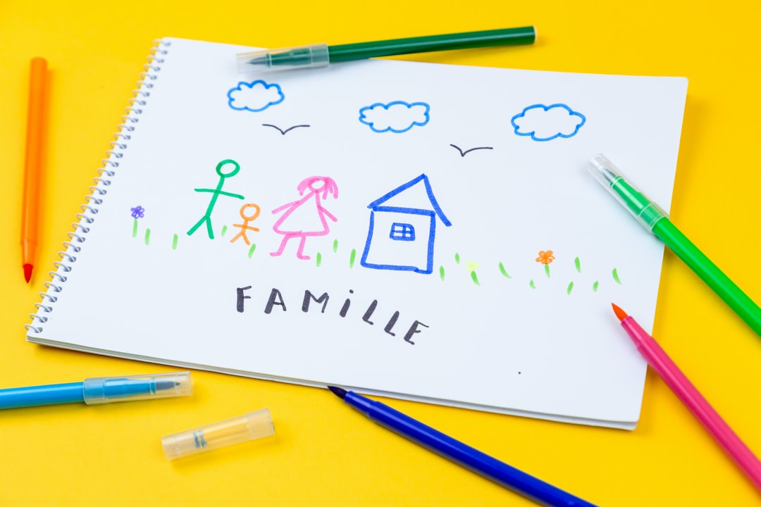 Image d'un bloc papier avec un dessin d'enfant représentant une maison et une famille, avec le mot famille dessous