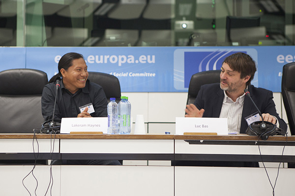 Close up of two people laughing as they are sat behind a desk at a meeting between community members and decision makers