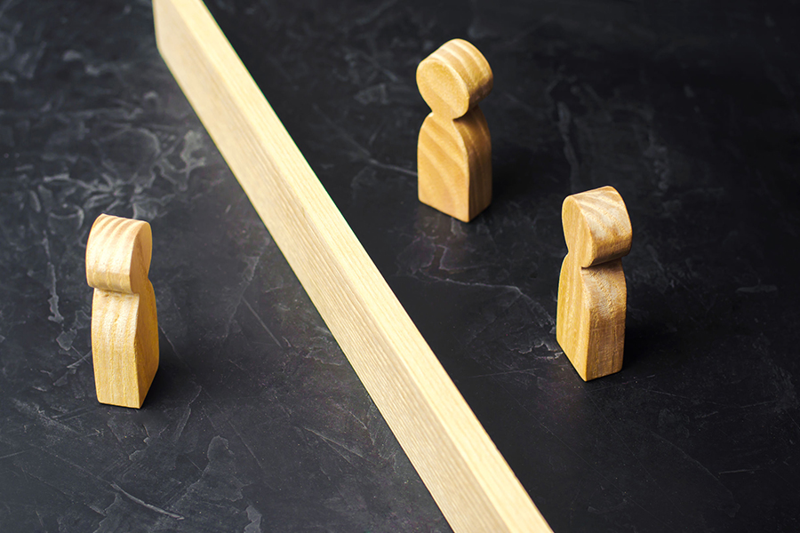 A wooden block with one wooden figure on one side and two wooden figures on the other side.