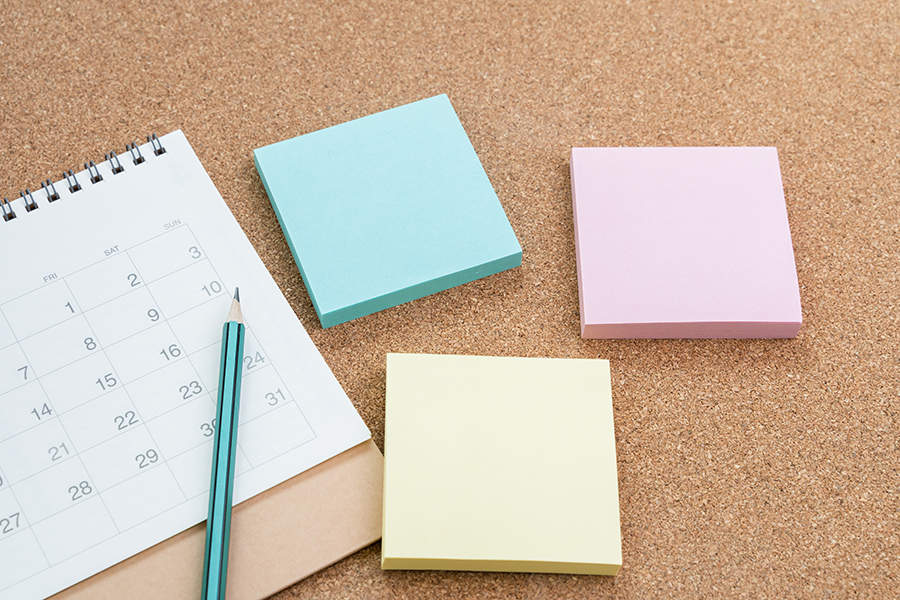 Three stacks of different-coloured sticky notes and a calendar with a pencil.