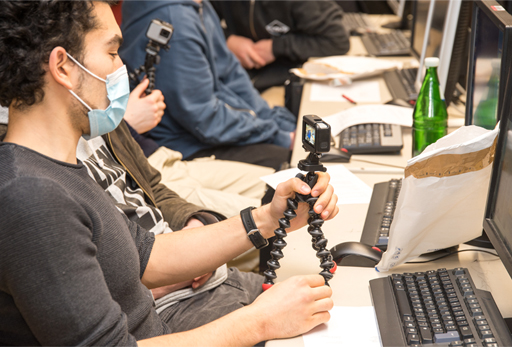 Ein Schüler, der an einem Schreibtisch sitzt und auf den Bildschirm einer GoPro-Kamera schaut