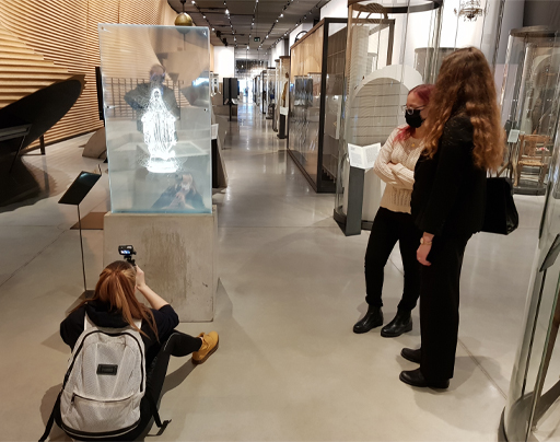 Estudiante grabando una obra expuesta en el Museo Nacional de Estonia mientras otros dos estudiantes la observan