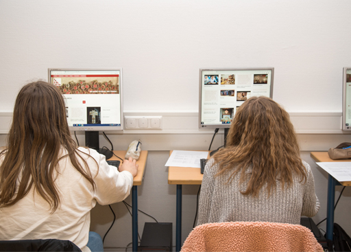 Dwie uczennice oglądają stronę internetową RETOPEA, siedząc przy stolikach z komputerami plecami do kadru.