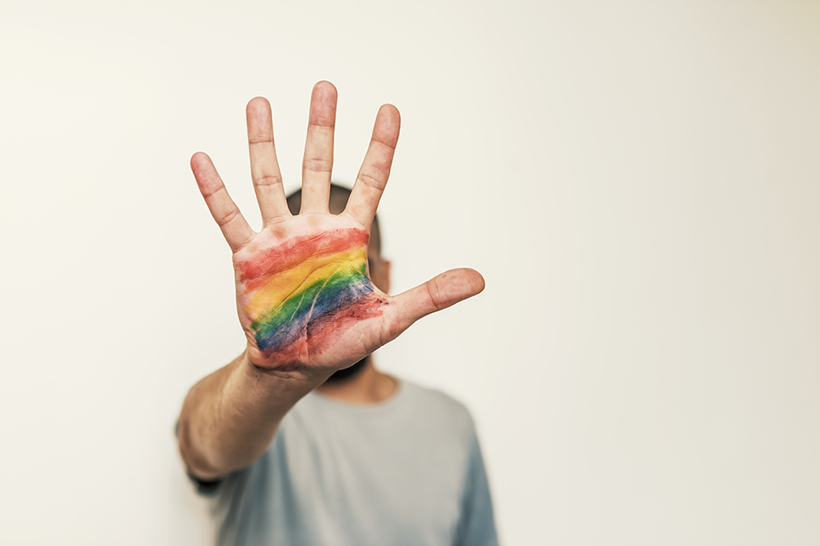An image of the palm of a human hand, painting in rainbow colours.