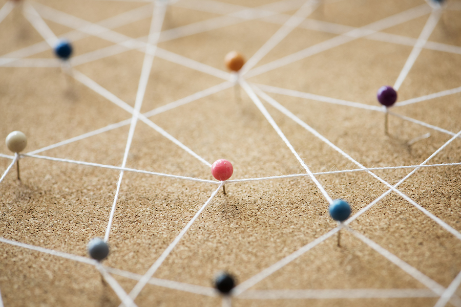 An image of pins on a cork noticeboard all joined together with thread.