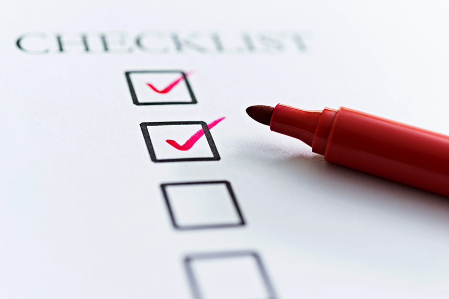 An image of a piece of paper with checklist printed at the top and below it a series of tick boxes. A red pen is laying on the paper and two of the tick boxes have red ticks in them.