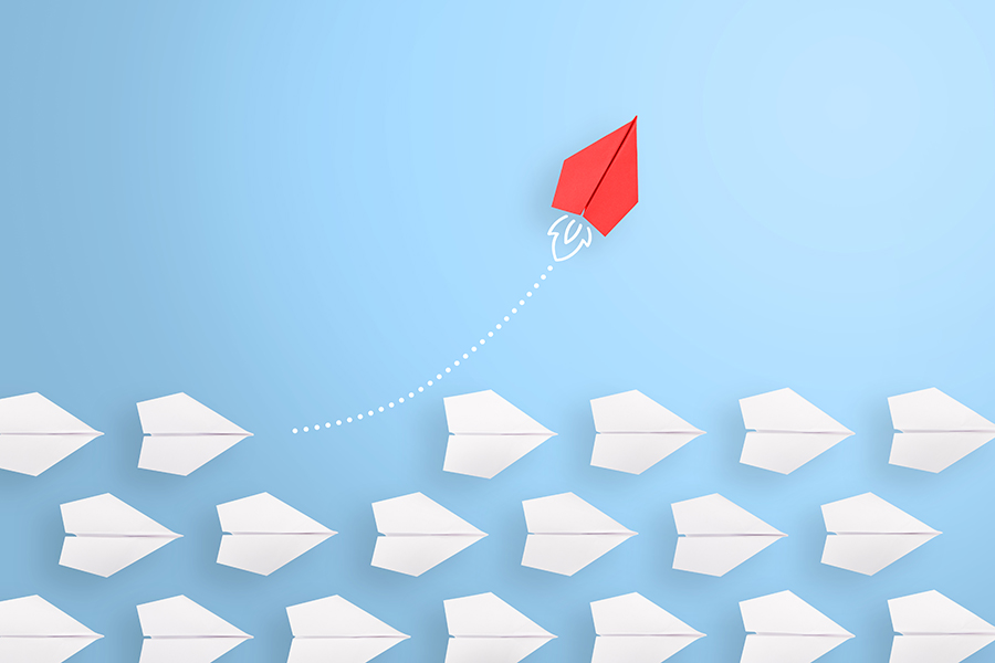 An illustration of several white paper airplanes all heading from left to right across the image. A red paper airplane is flying in an upwards direction.