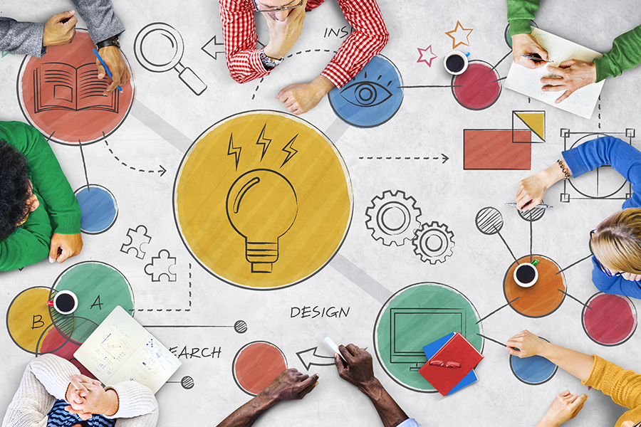 An overhead image looking down on a table where people are writing, drawing and being creative. The surface is covered in ill