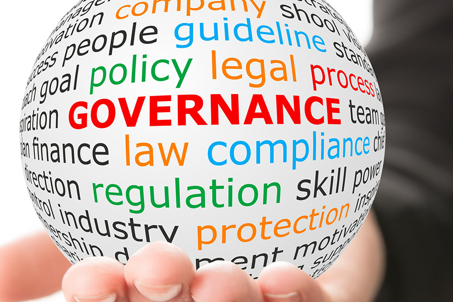 An image of a ball in the palm of a hand. The ball has multiple words printed on it, such as governance, law, compliance, policy, legal, guideline, regulation, and many more.