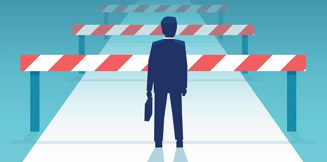 A man holding a briefcase but faced with multiple barriers on the read