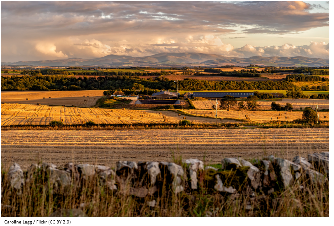 A large Scottish farm with hay bales at sunset.