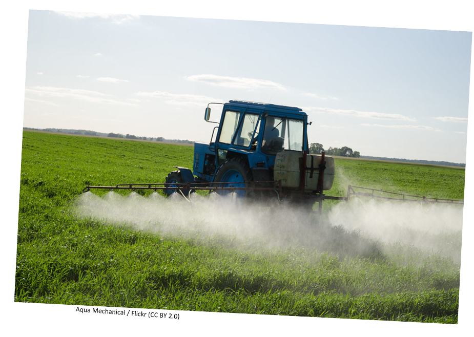 A tractor in a field spraying pescticide. 