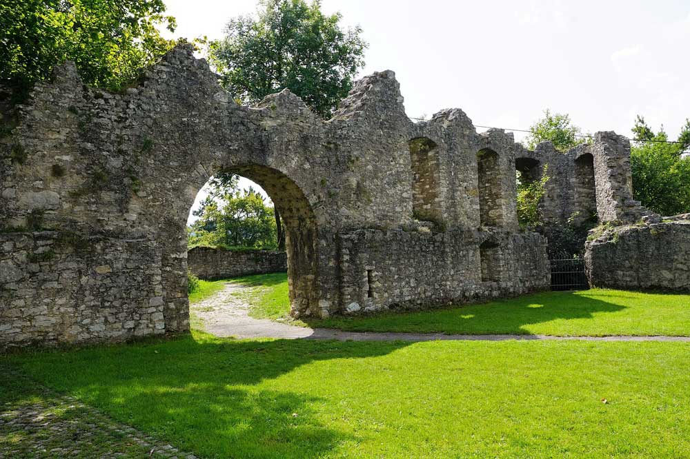 A path leading through an archway in an ancient ruin which has become a garden wall.