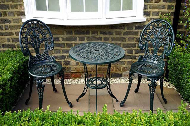 wrought iron table and chairs sitting on small paved patio.