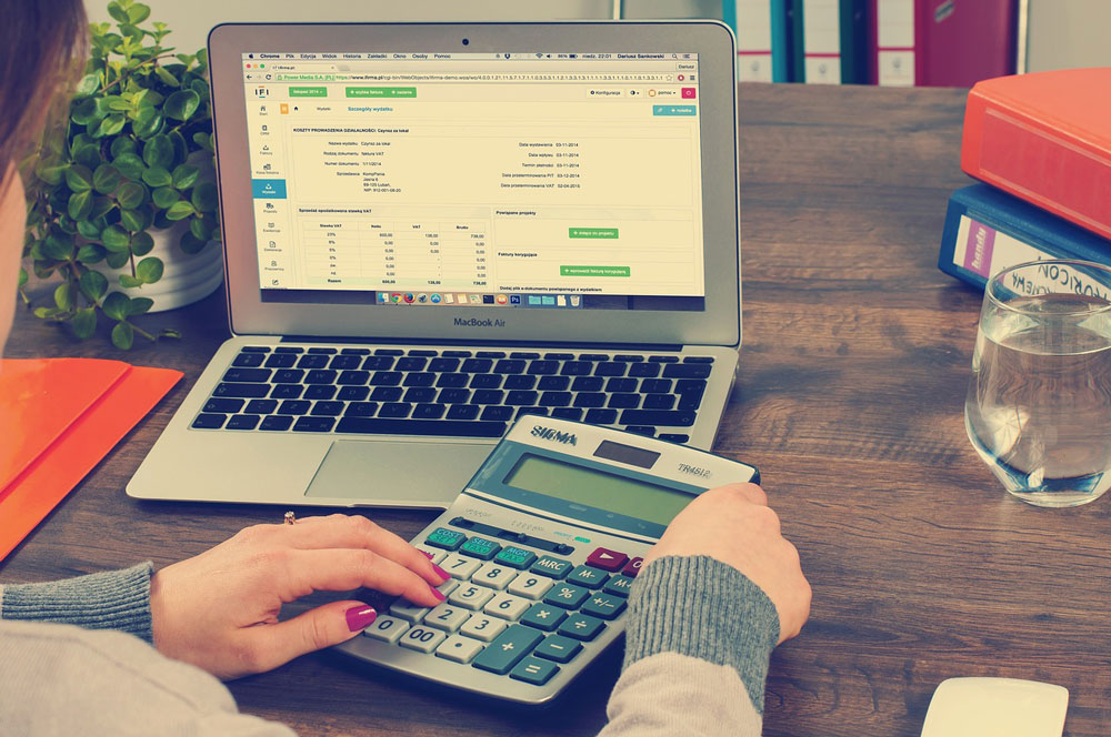 A person working on a spreadsheet which is open in a laptop on a desk.