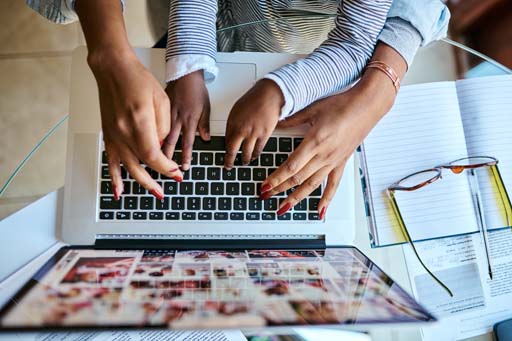 This is a photograph of a woman’s and a child’s hands on a laptop.