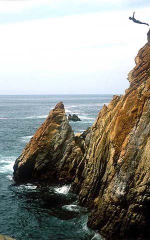 A photograph of a person jumping off a cliff into the sea.