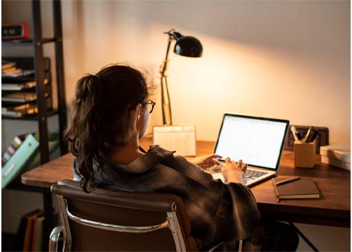 A photograph of a person at a desk typing on a laptop.