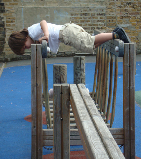 A photograph of a boy playing alone on an indoor climbing set