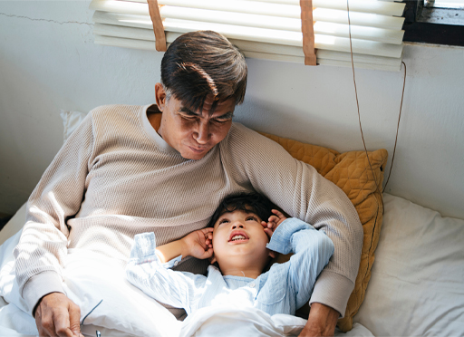This is a photograph of a child reading with an adult while in bed.