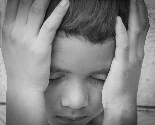 This is photograph of a child with their head in their hands.