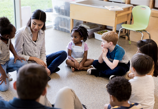This is a photograph of a woman and a group of children sitting in a circle.
