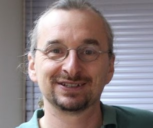 Dr Pascal Patrick Matzler smiling into the camera and wearing small round glasses