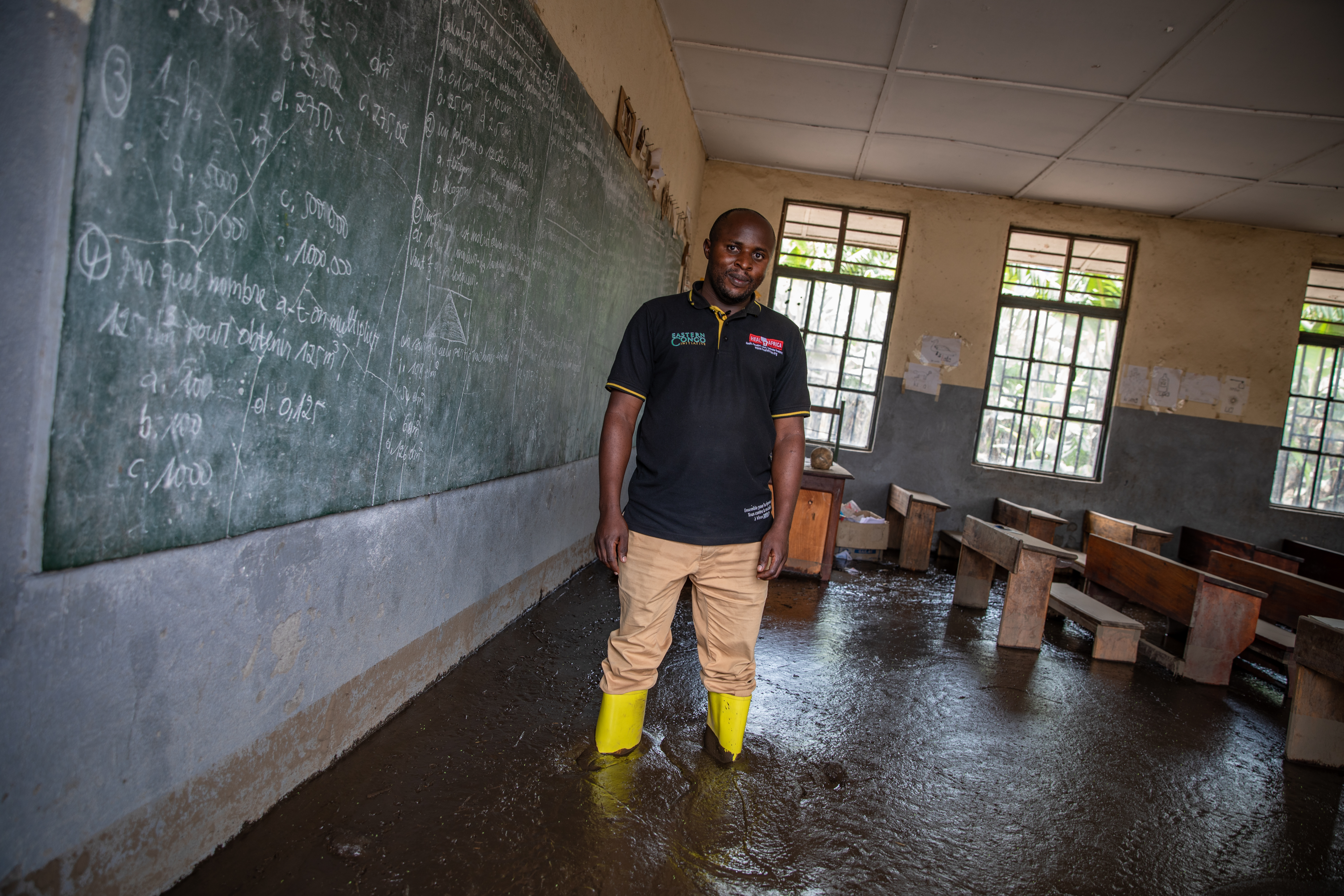 Photograph of a teacher standing in his flooded classroom.