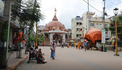 A temple in Nepal with people sitting and walking by